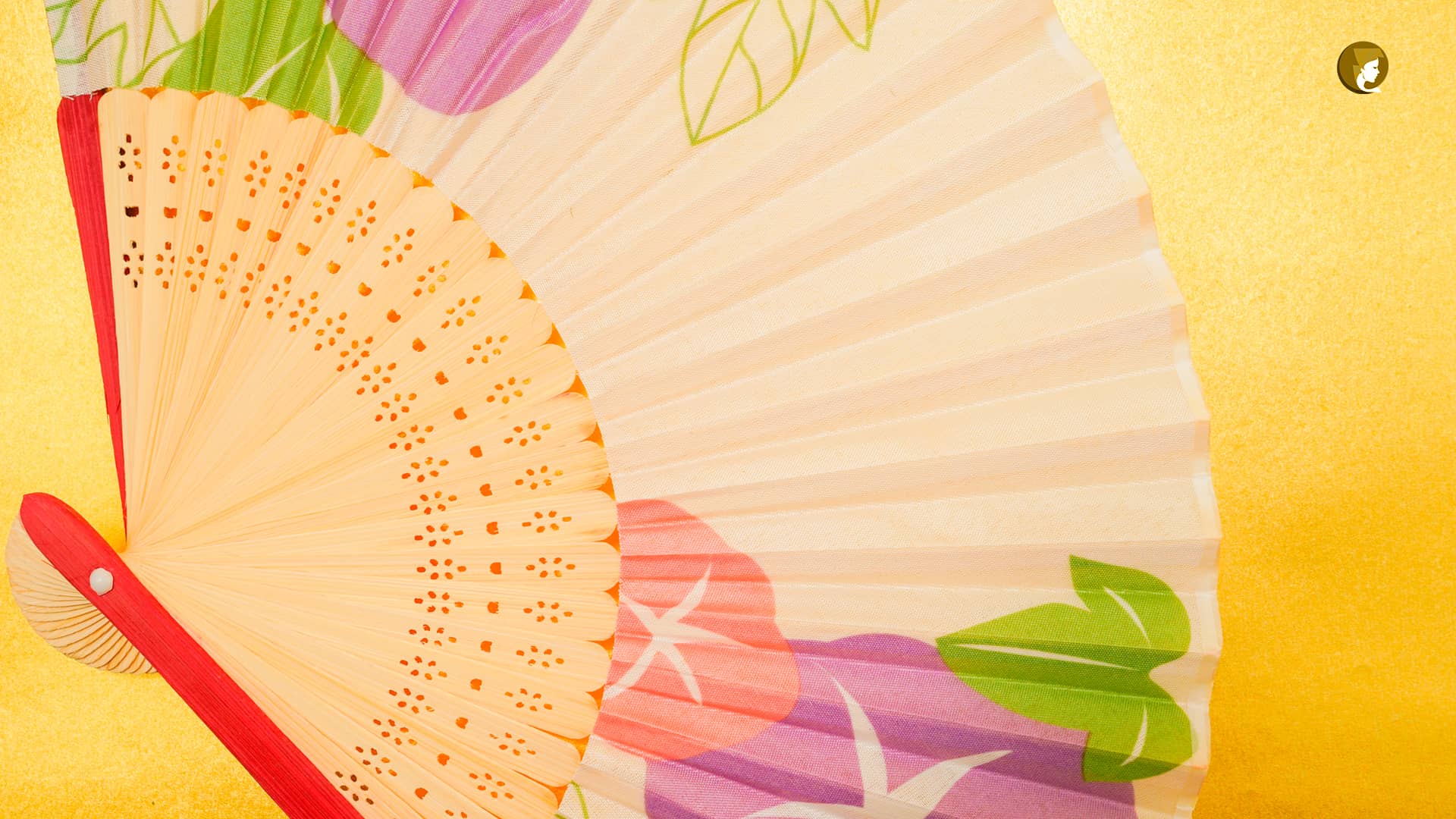 Abanico japonés con motivos florales sobre fondo dorado.