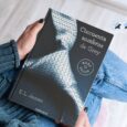 Resumen de Cincuenta sombras de Grey: una mujer sostiene el libro de E. L. James junto a una valoración de dos estrellas y media